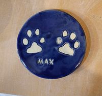 A circular imprint of a dog's paws made of clay &amp; with a blue background